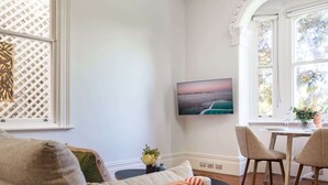 A living room with a sofa, a coffee table, and a TV mounted on the wall.