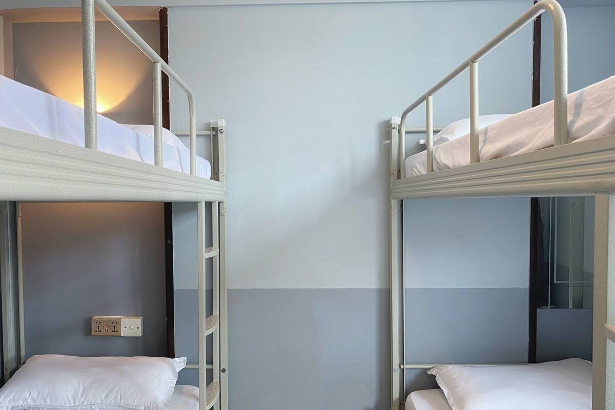 A room with two bunk beds, a small table, and a wall socket.