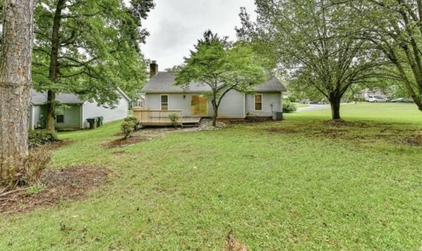 A single-story house with a front porch, surrounded by a well-maintained lawn and trees.