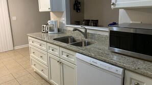 A kitchen with white cabinets, a granite countertop, a stainless steel sink, a coffee maker, a microwave, and a dishwasher. - Amazing home for 6 ! (Charlotte)