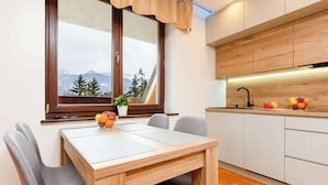 A modern kitchen with wooden cabinets, a white countertop, and a window with a view of mountains. - Suite with Mountain View | Gym | Sauna. (Koscielisko)
