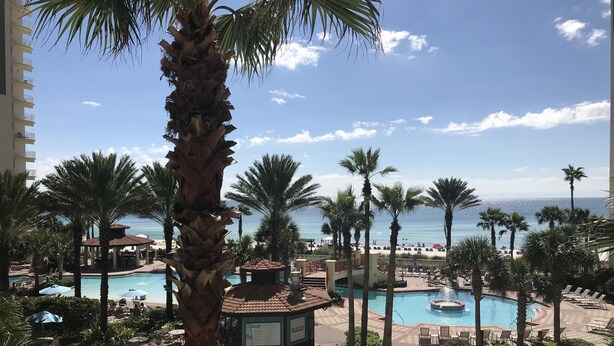 A resort with multiple swimming pools, palm trees, and a view of the ocean.
