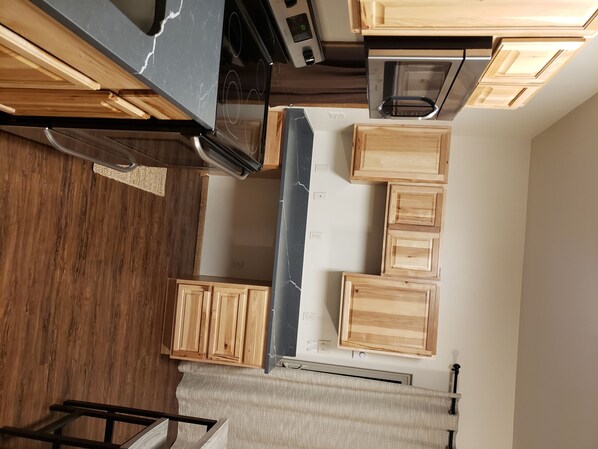 Una cocina con armarios de madera, encimera de mármol y horno empotrado.