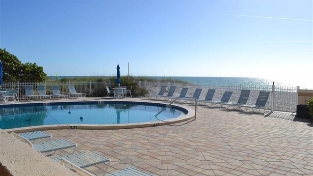 A pool area with lounge chairs and a view of the ocean. - Beachcomber unit 605 (Longboat Key)
