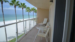 A balcony with a view of the beach and ocean. There are two white chairs and a small table. - Beachcomber unit 302 (Longboat Key)