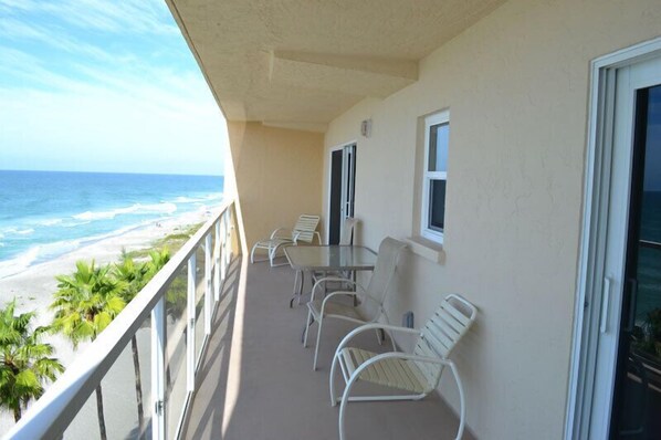 A balcony with a view of the beach and ocean, furnished with white chairs and a table. - Beachcomber unit 604 (Longboat Key)