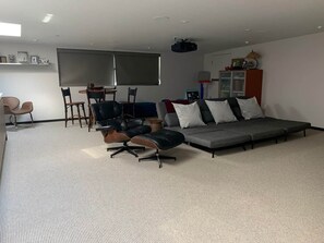 A modern living room with a grey sofa, black and brown chairs, a small table, and a projector screen. - Luxury Incline Village Vacation Rental (Incline Village)