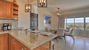 Una cucina moderna con piani di lavoro in granito, mobili in legno e un'area pranzo con tavolo e sedie.
