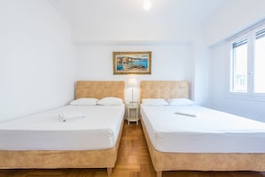 A hotel room with two single beds, a nightstand with a lamp, and a painting on the wall.