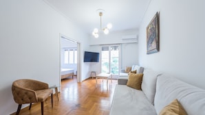 Een moderne woonkamer met een witte bank, een bruine fauteuil en een glazen salontafel.