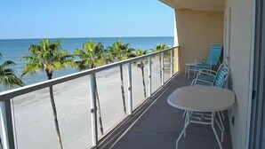 A balcony with a view of the beach and ocean. There are blue chairs and a white table. - Beachcomber unit 502 (Longboat Key)
