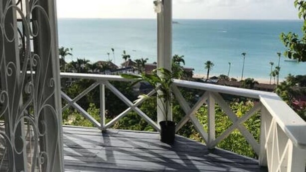 A wooden deck with a railing overlooking a beach and ocean. - View 61 Hibiscus with Private pool & Beach View (St John's)