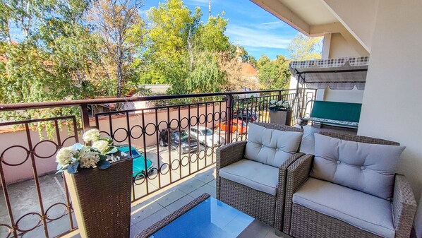 A balcony with wicker furniture, a small table, and a blue mat.