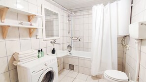 A modern bathroom with a washing machine, sink, and toilet.