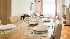 Un coin repas avec une table en bois mise pour quatre personnes, comprenant des assiettes, des verres et des couverts.