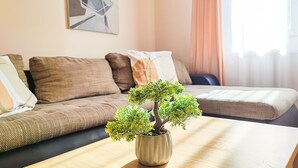 Un salon avec un canapé, une table basse et un bonsaï dans un pot.