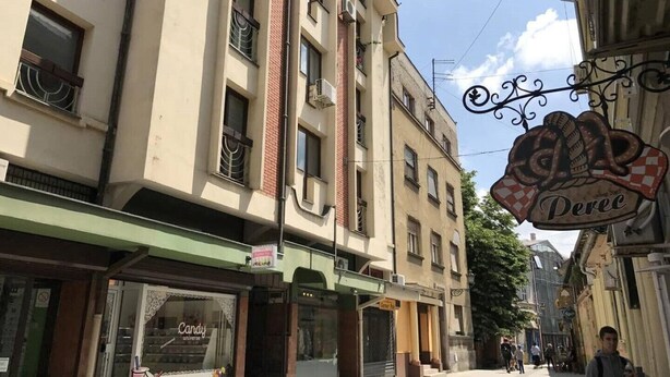 Vista de la calle con un edificio que muestra el letrero 'Perec', una tienda de dulces y una tienda 'Candy Universe'.