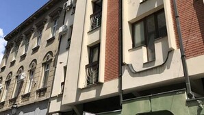 Un edificio de varios pisos con estilo arquitectónico clásico, que presenta una combinación de fachadas de ladrillo y enlucido, ventanas amplias y balcones.