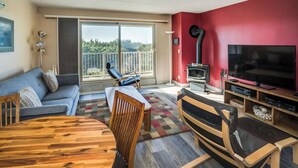 A living room with a sofa, a wooden dining table, a TV, and a fireplace. - Gearhart House G603 (Gearhart)