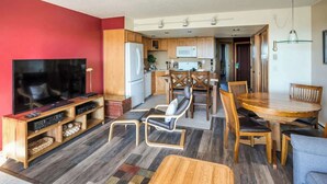 A modern living room with a flat-screen TV, wooden entertainment unit, and a dining area with a wooden table and chairs. - Gearhart House G603 (Gearhart)