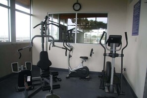 A gym with exercise equipment, a window, and a clock.