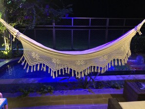 A hammock over a pool with a decorative canopy, surrounded by a fence and plants. - Luxury house in Atapuz with private pool, facing p pontal de maria flour (Goiana)
