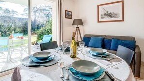 A dining area with a table set for four, a lamp, and a framed picture on the wall. - Astrida by Interhome (Carnac)
