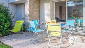 A patio with a table and four chairs, a stone pillar, and a glass door leading to a room. - Astrida by Interhome (Carnac)