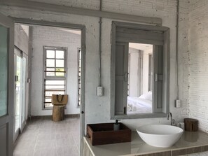 Un baño moderno con un espejo grande, un lavamanos blanco y un tocador de madera.