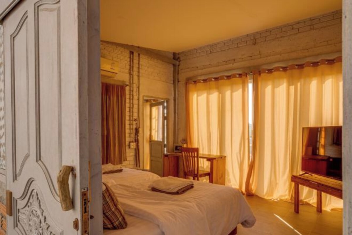 A hotel room with a bed, a desk, a chair, and a television.