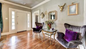 Una habitación con piso de madera, un sofá, dos sillas, una mesa, un espejo y una decoración con un cráneo de toro.