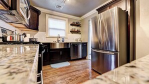 Una cocina moderna con electrodomésticos de acero inoxidable, encimera de mármol y suelo de madera.