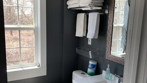 Un baño con inodoro blanco, lavabo con espejo y ventana.