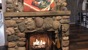 A stone fireplace with a painting above it, a lit fire, and a chandelier.
