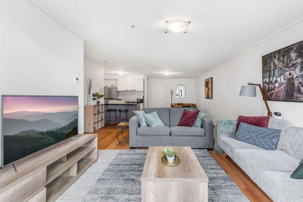 A modern living room with a grey sofa, a coffee table, and a TV.