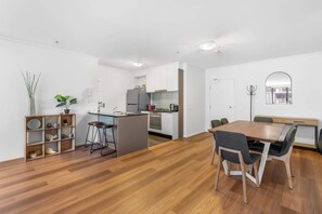 A modern kitchen with a central island, a dining area with a wooden table and chairs, and a large mirror on the wall.