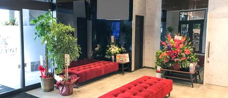 A modern lobby with a red bench, potted plants, and a large window.