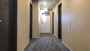 A hotel hallway with carpeted floors, doors on both sides, and a ceiling with recessed lighting. - Hotel Livemax Fukushima Koriyama Ekimae (Koriyama)