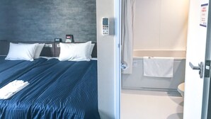 A modern hotel room with a large bed, a control panel, and a visible bathroom with a toilet and towel. - Hotel Livemax Fukushima Koriyama Ekimae (Koriyama)