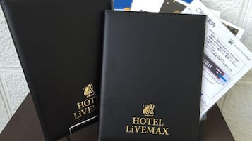 Dos carpetas negras con la marca 'HOTEL LIVEMAX' y un logo, sobre una mesa con algunos documentos.