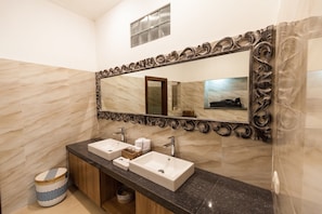A bathroom with two sinks, a large mirror, and a vanity with storage.