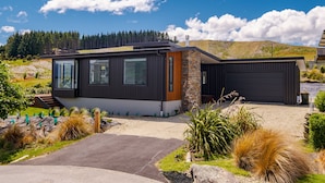 Une maison moderne dotée d’un garage, d’une allée et d’un jardin bien entretenu.