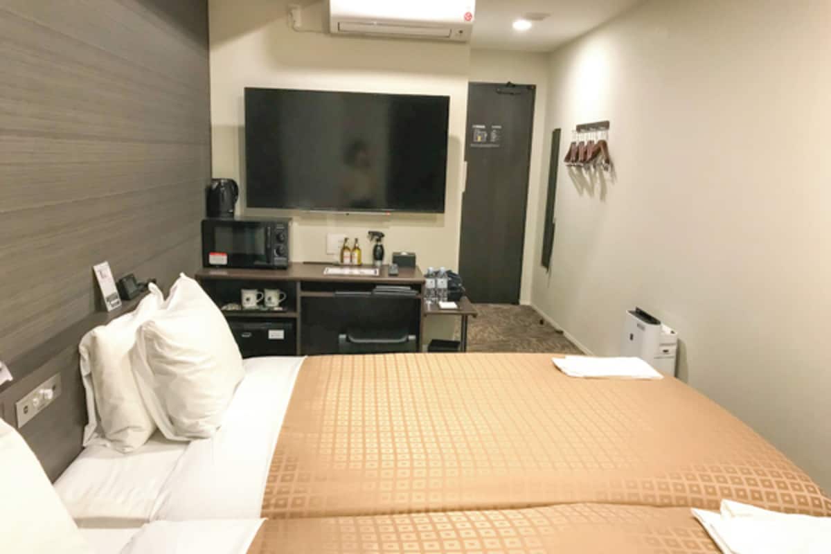 A hotel room with a bed, a desk, a flat-screen TV, a microwave, and a coffee maker.