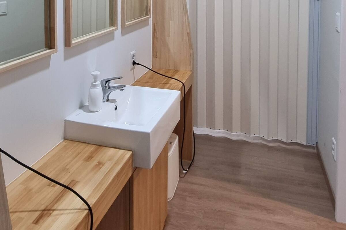 A modern bathroom with a wooden vanity, a large mirror, and a white sink.