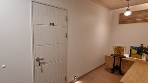 Una habitación con una puerta de madera marcada con el número 104, una pequeña mesa con un florero y dos cuadros enmarcados en la pared.
