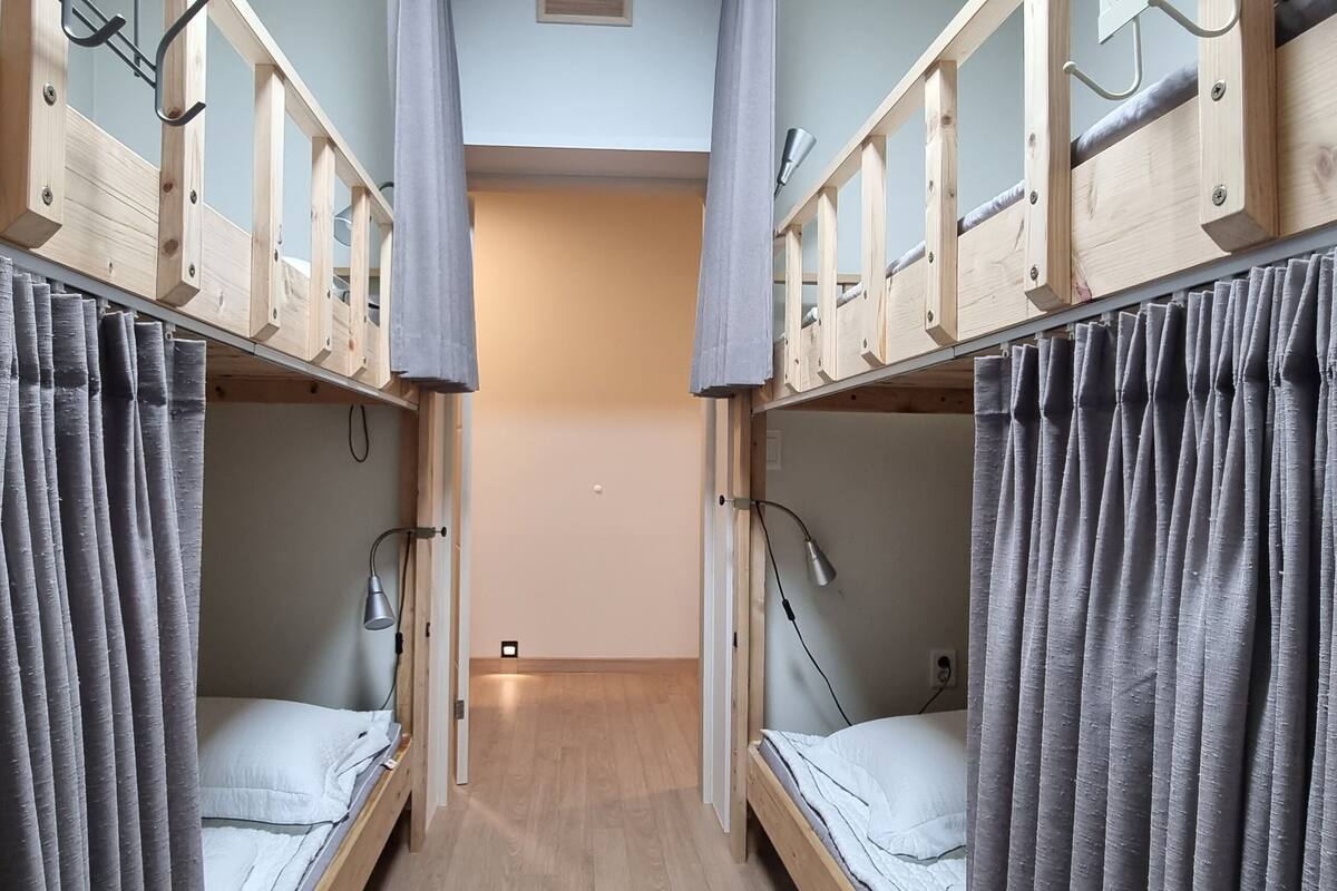 A room with two bunk beds, each with a headboard and a bedside lamp.