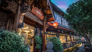 Un bâtiment traditionnel avec une façade en bois, une enseigne et un élément décoratif aquatique à l’avant.