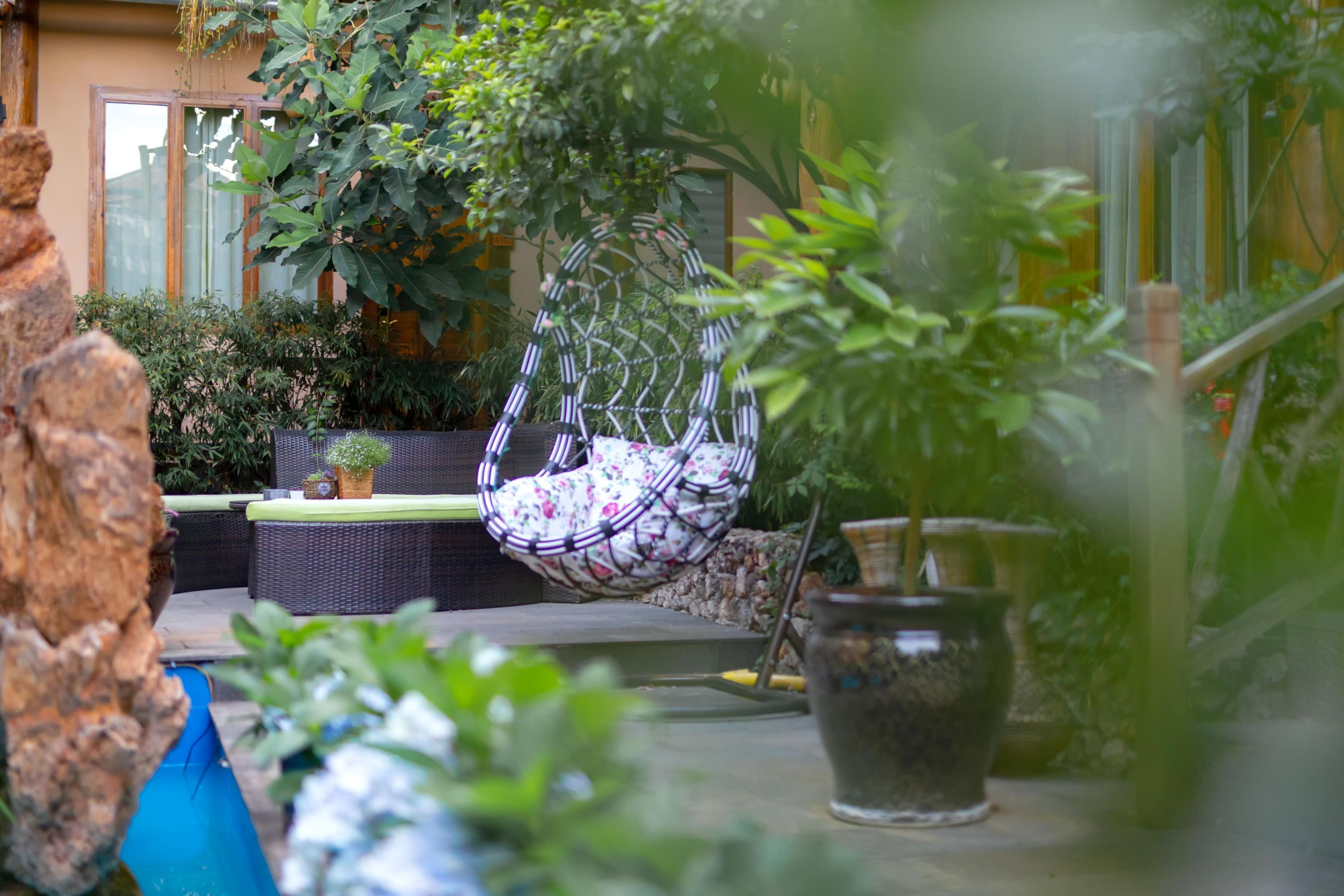 Eine Terrasse mit einer Hängematte, Gartenmöbeln und Blumentöpfen.