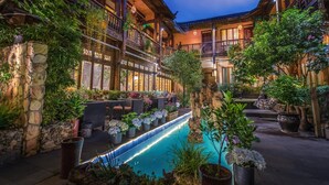 Une cour avec une piscine, des espaces de détente en plein air et une végétation luxuriante.