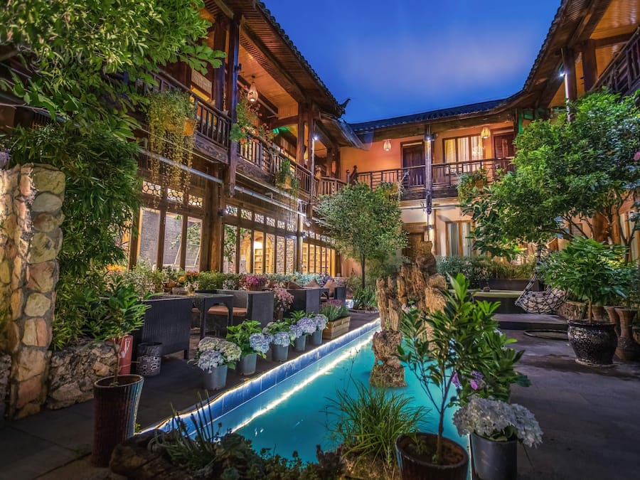 A courtyard with a pool, outdoor seating, and lush greenery.